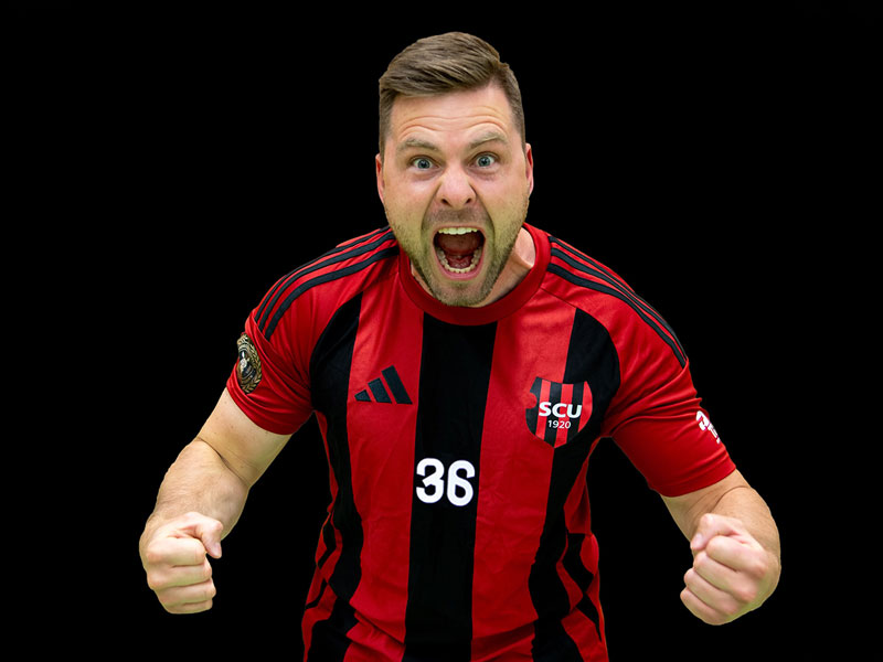 Jubelnder Handballspieler im rot-schwarzen SCU-Trikot vor schwarzem Hintergrund